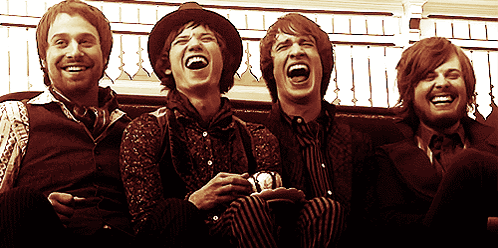 four men are sitting on a couch laughing together