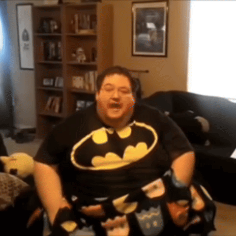 a man in a batman shirt is sitting in a chair