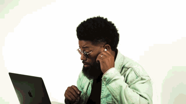 a man wearing sunglasses is sitting in front of a laptop