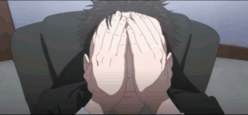 An anime man sits hunched forward with both hands covering his face.