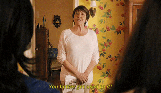 a woman is standing in front of a yellow wall and says you better get used to it