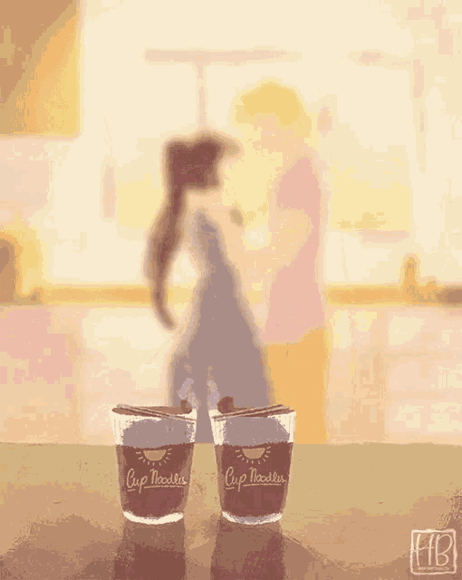two cup noodles are on a table in front of a man and woman