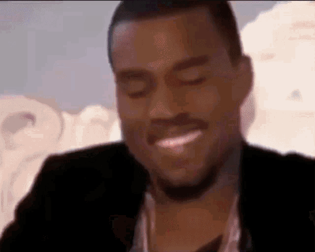 a man in a suit is smiling with his eyes closed