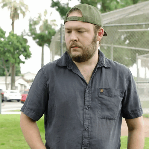 a man with a beard wearing a black shirt and a green hat that says ' abercrombie ' on it