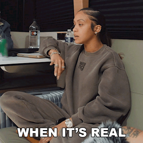 a woman wearing a sweatshirt that says when it 's real sits on the floor