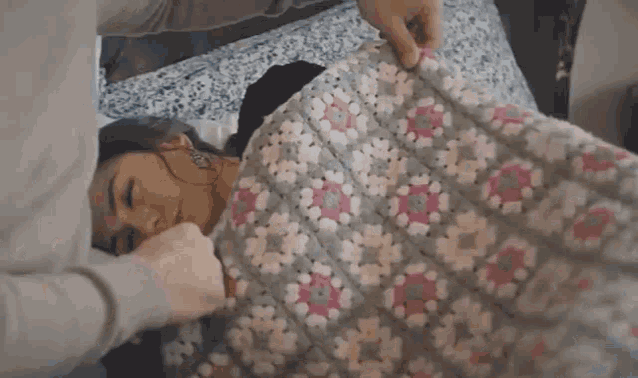 a woman is laying on a bed with a blanket on her back .