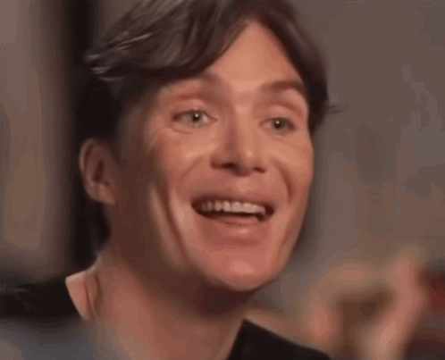 A man laughs nervously while looking off-camera.