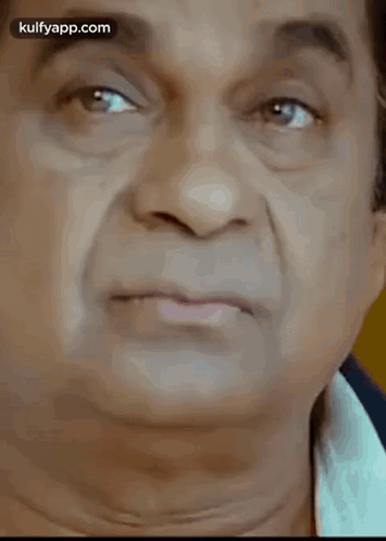 a close up of a man 's face with his eyes closed and a white shirt on .