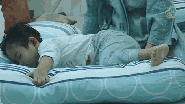 A person sleeps face-down across a bed in a hospital-like room.