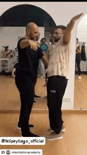 two men are dancing in front of a mirror in a room .