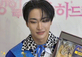 a young man in a polka dot shirt is holding a gift box .