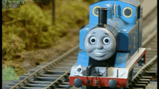 a thomas the tank engine is on the tracks and smiling