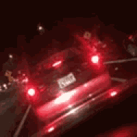 a car is driving down a highway at night with its tail lights on .