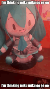 a stuffed miku doll is sitting on a table with the caption i 'm thinking miku miku