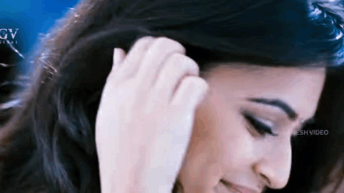 a close up of a woman 's face with her hand in her hair .