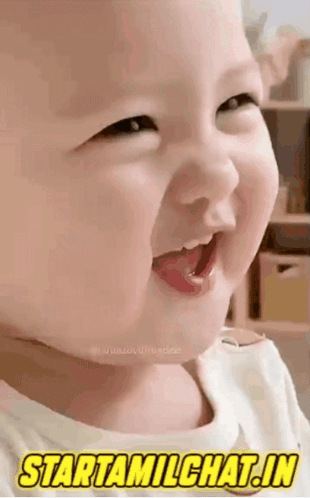 A laughing baby smiles broadly in a vertical clip.