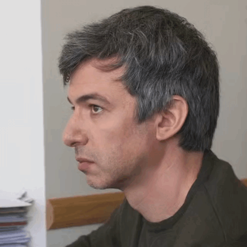 a man with gray hair and a beard looks at something