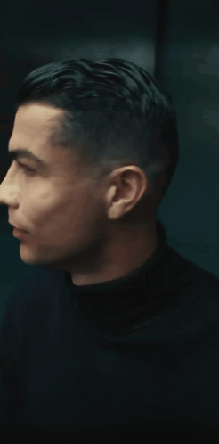 a man in a black turtleneck is smiling and looking to the side