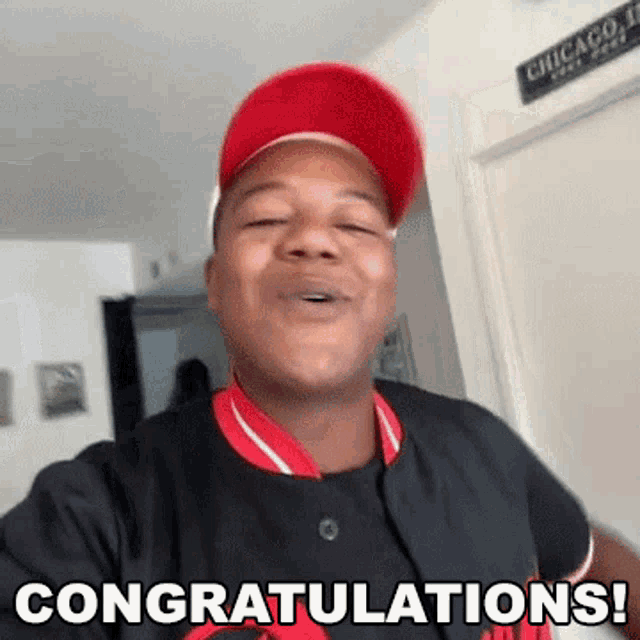 a man wearing a red hat and a black shirt is congratulating someone with a thumbs up .