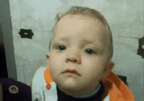 A baby looks blankly at the camera in a close-up.