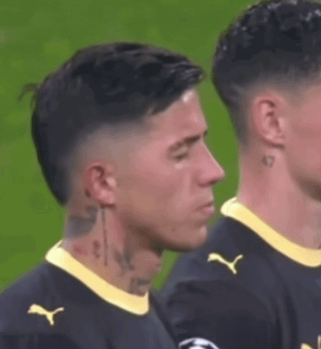 a soccer player with a tattoo on his neck is standing next to another soccer player on the field .