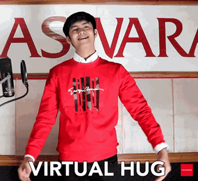 a man wearing a red sweater is standing in front of a sign that says virtual hug