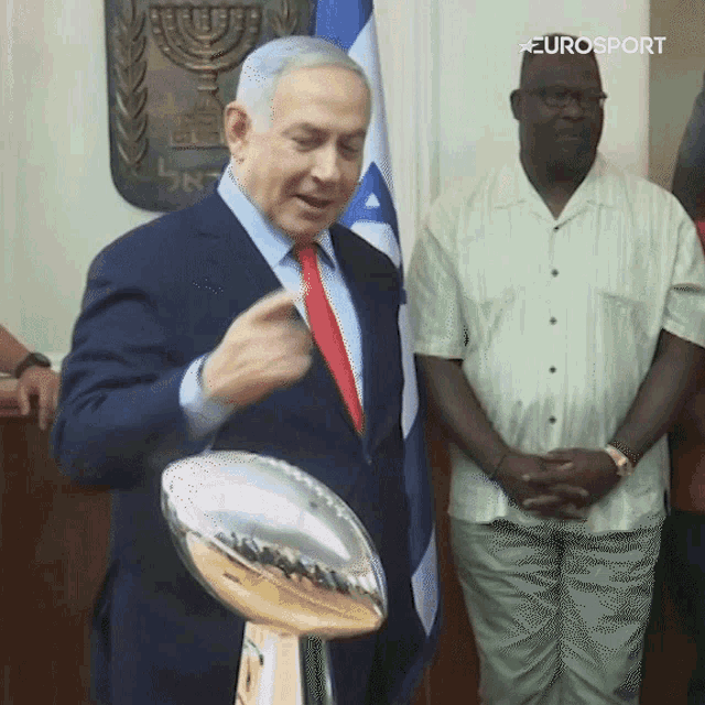 a man in a suit and tie is holding a trophy with eurosport written on it