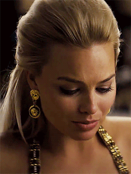 a close up of a woman 's face wearing earrings and a necklace