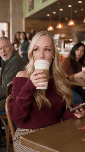 a woman sits at a table drinking a cup of coffee with lifehanae written on the bottom