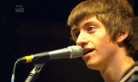 a close up of a person singing into a microphone with bbc three on the bottom right