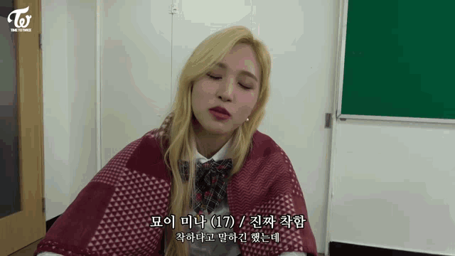 a girl with blonde hair is wearing a plaid scarf around her shoulders and the word twice is on the bottom right
