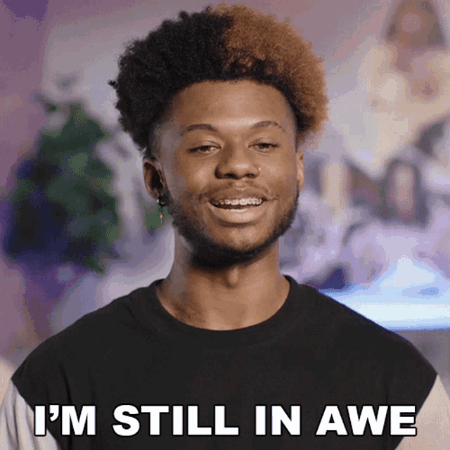 a man with braces on his teeth is smiling and says " i 'm still in awe "