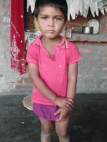 a little girl wearing a pink shirt and shorts