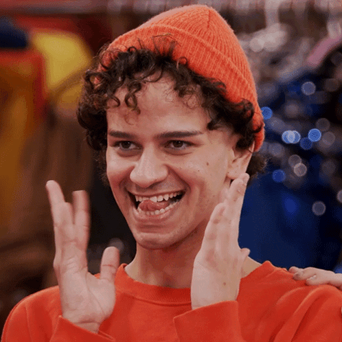 a young man with curly hair wearing an orange hat and an orange sweater