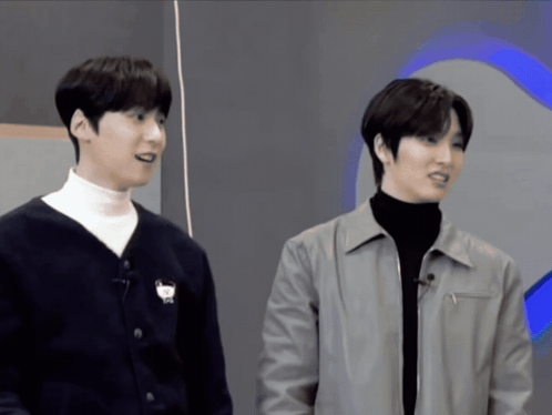 two men are standing next to each other and one of them has a cat on his sweater