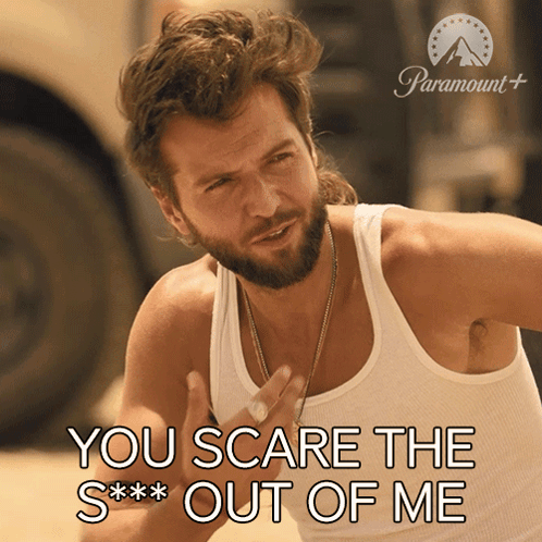 a man with a beard wearing a white tank top says you scare the s *** out of me