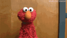 Elmo looks blankly forward in a dim room.