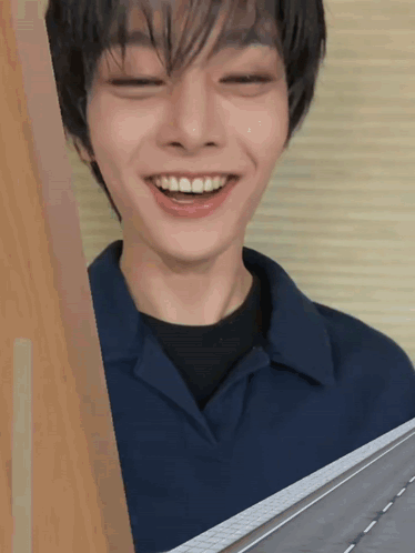 A smiling young person peeks around a doorway in a close-up reaction shot.