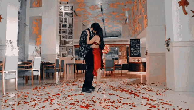 a man and a woman are hugging in a room covered in red petals