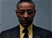 a man in a suit and tie with glasses looks at the camera