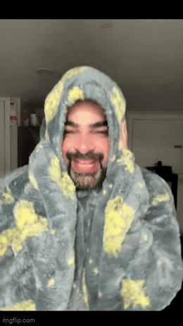 A person in a paint-splattered hoodie smiles under “Ouch Ouch Ouch.”