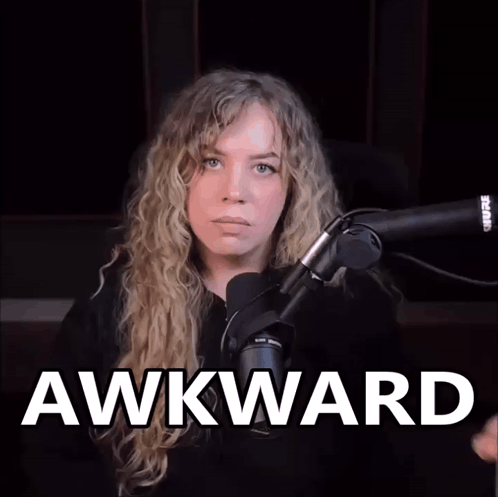 A woman at a microphone stares ahead as large text reads “AWKWARD.”