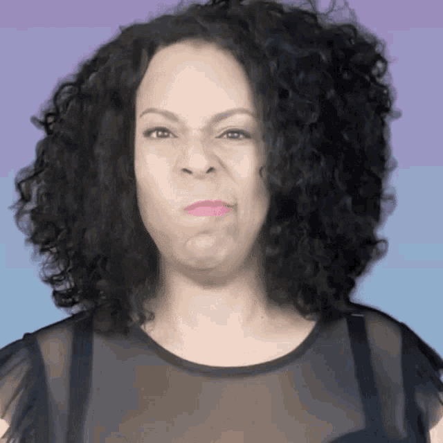 a woman with curly hair is making a funny face while wearing a black shirt .