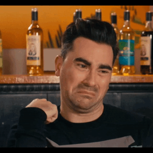 David Rose recoils with a pained expression at a bar.