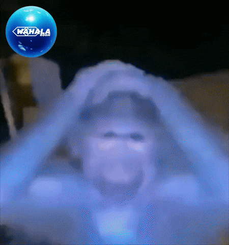 A blurry figure holds both hands on their head in distress.