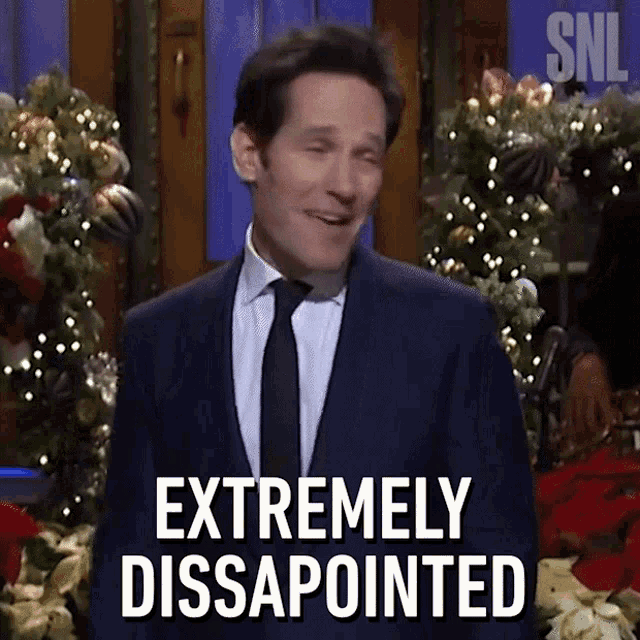 a man in a suit and tie says " extremely disappointed " in front of a christmas tree