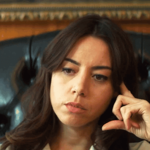A woman rests her head on her hand with an unimpressed, awkward expression.