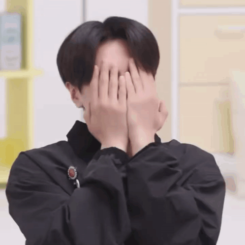 a man is covering his face with his hands and making a funny face .
