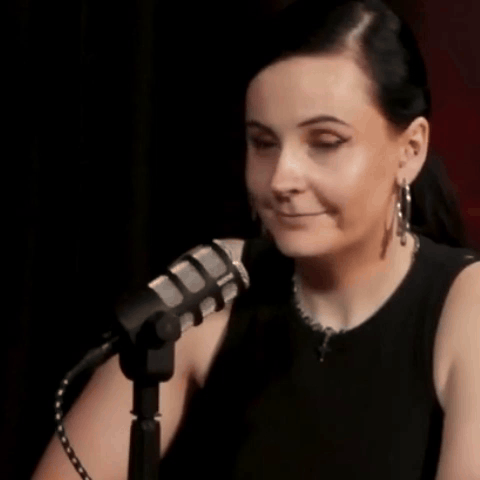 a woman is sitting in front of a microphone with the words indeed written on the bottom