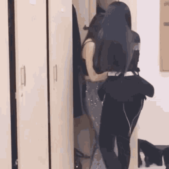 two women are standing in a locker room .